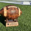 Personalized handcrafted wooden football gift with engraved base on display stand.