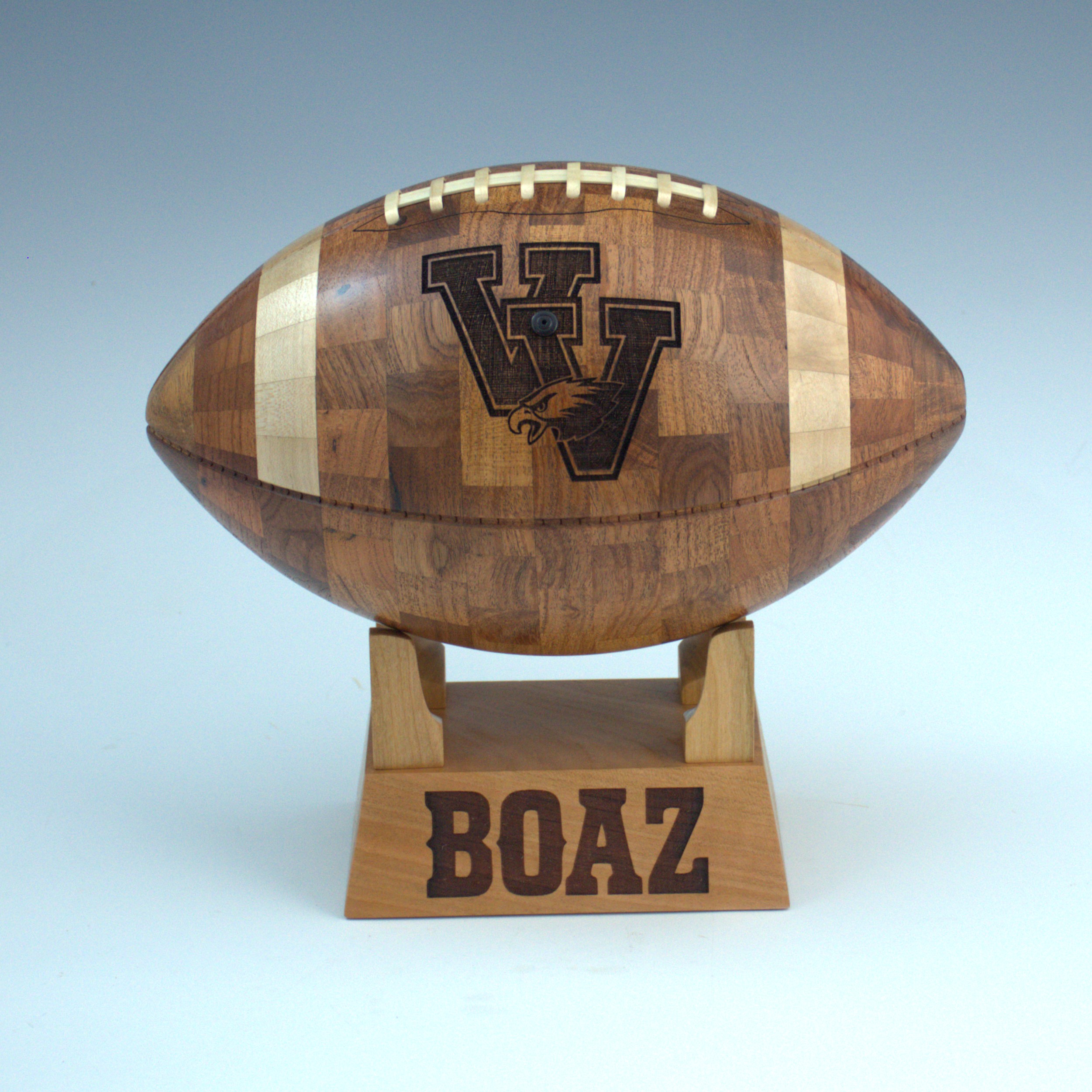 Handcrafted wooden football award with engraved high school logo and personalized wooden base on a hardwood stand.
