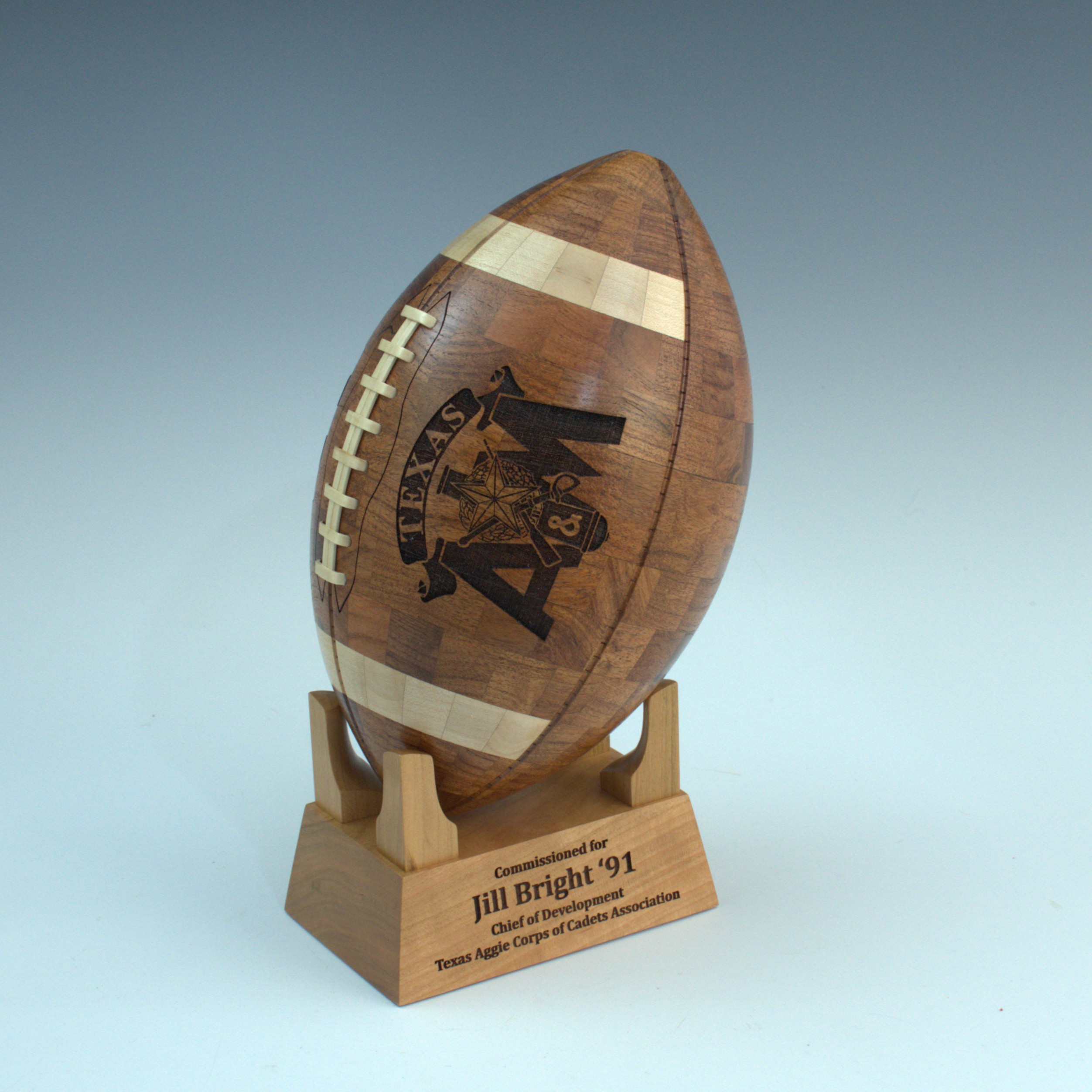 Custom handcrafted Texas A&M wooden football featuring wooden laces, engraved logo, and personalized display stand.